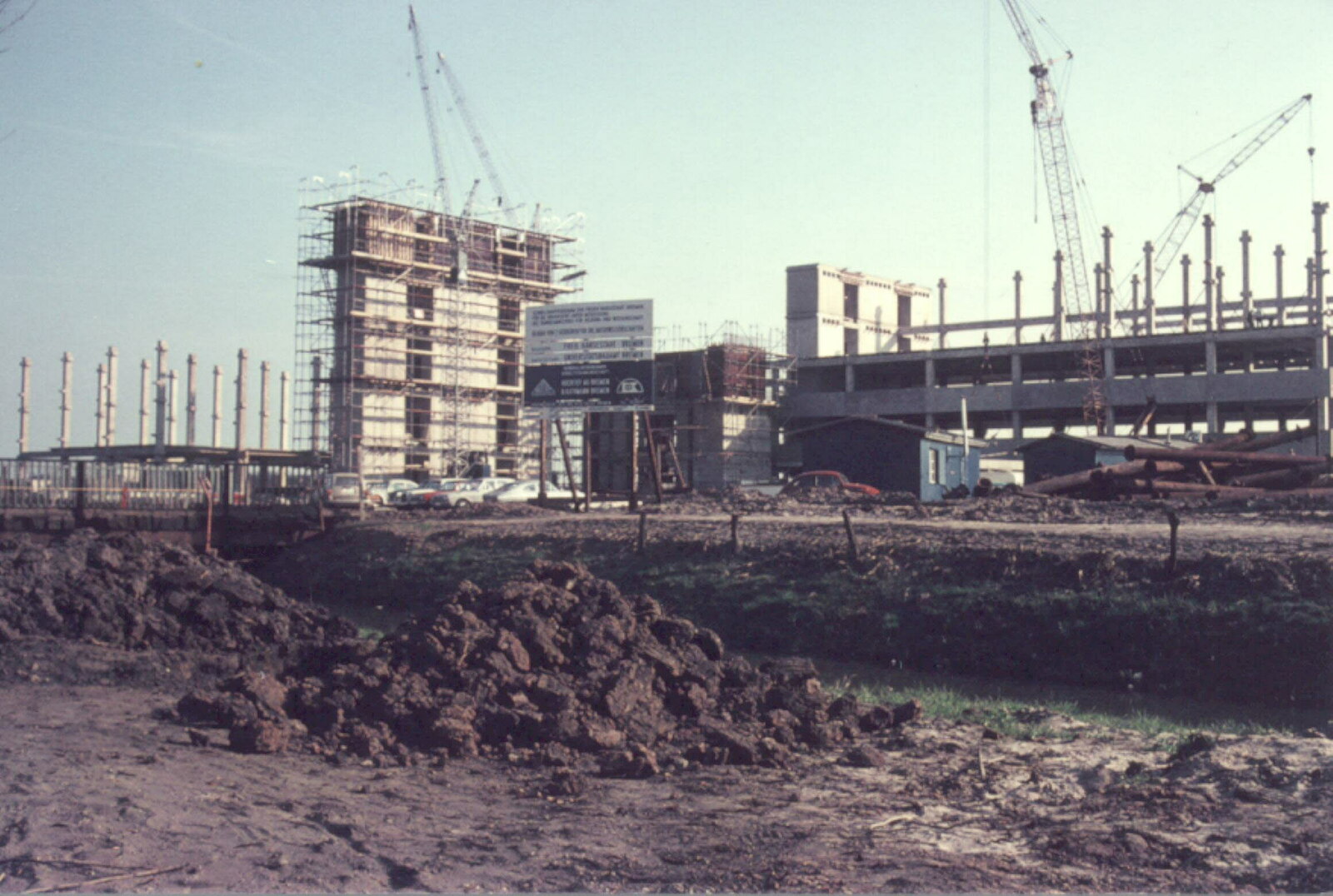 Blick über die kleine Wümme auf die Baustelle des Gebäudes im Sommer 1970. Im Vordergrund aufgeworfene Erdhaufen. Links stehen nur Pfeiler und Versorgungs- und Fahrstuhlschächte, der Bau des rechten Teils des Gebäudes ist weiter fortgeschritten. Hier sind