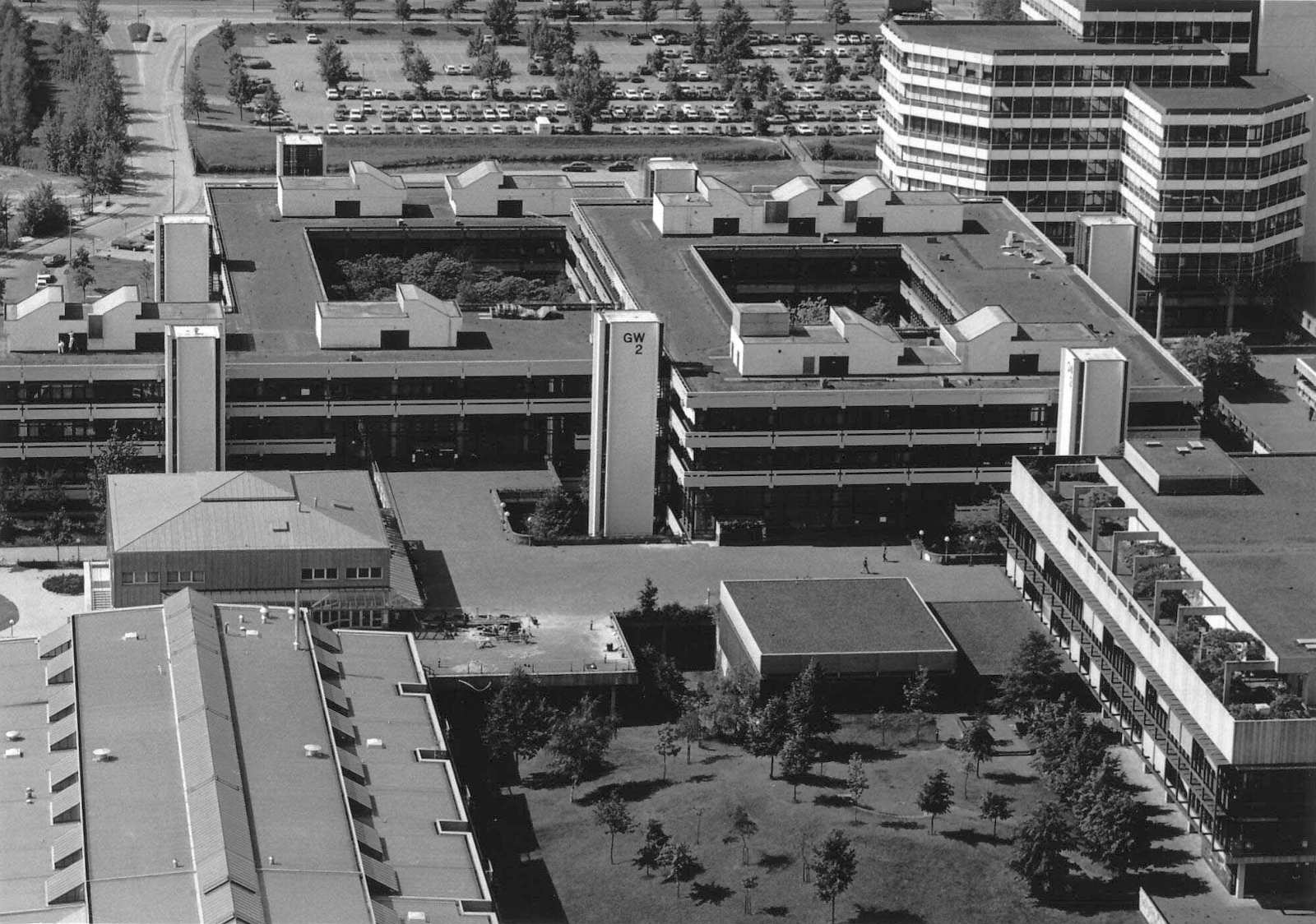 Blick von Osten auf das Gebäude mit seinen sieben Treppenaufgängen. Rechts oben überragt das Mehrzweckgebäude das GW 2. Am oberen Rand verläuft die Parkallee, an der sich unterhalb der Parkplatz der Universität anschließt. Links daneben verläuft die Enriq