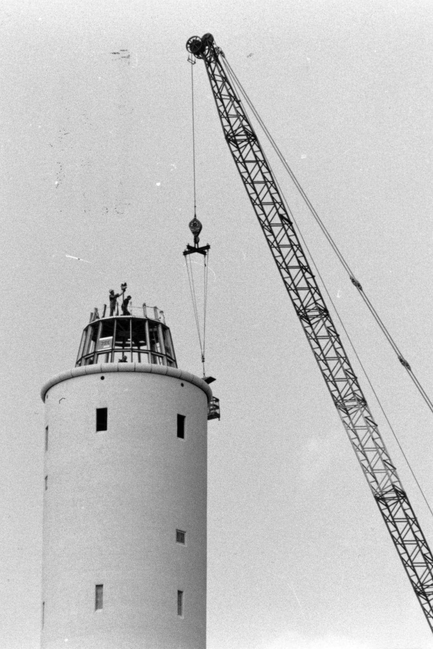 Vier Fotos zeigen die schrittweise Montage der kegelförmigen Spitze auf dem Fallturm im August 1989.